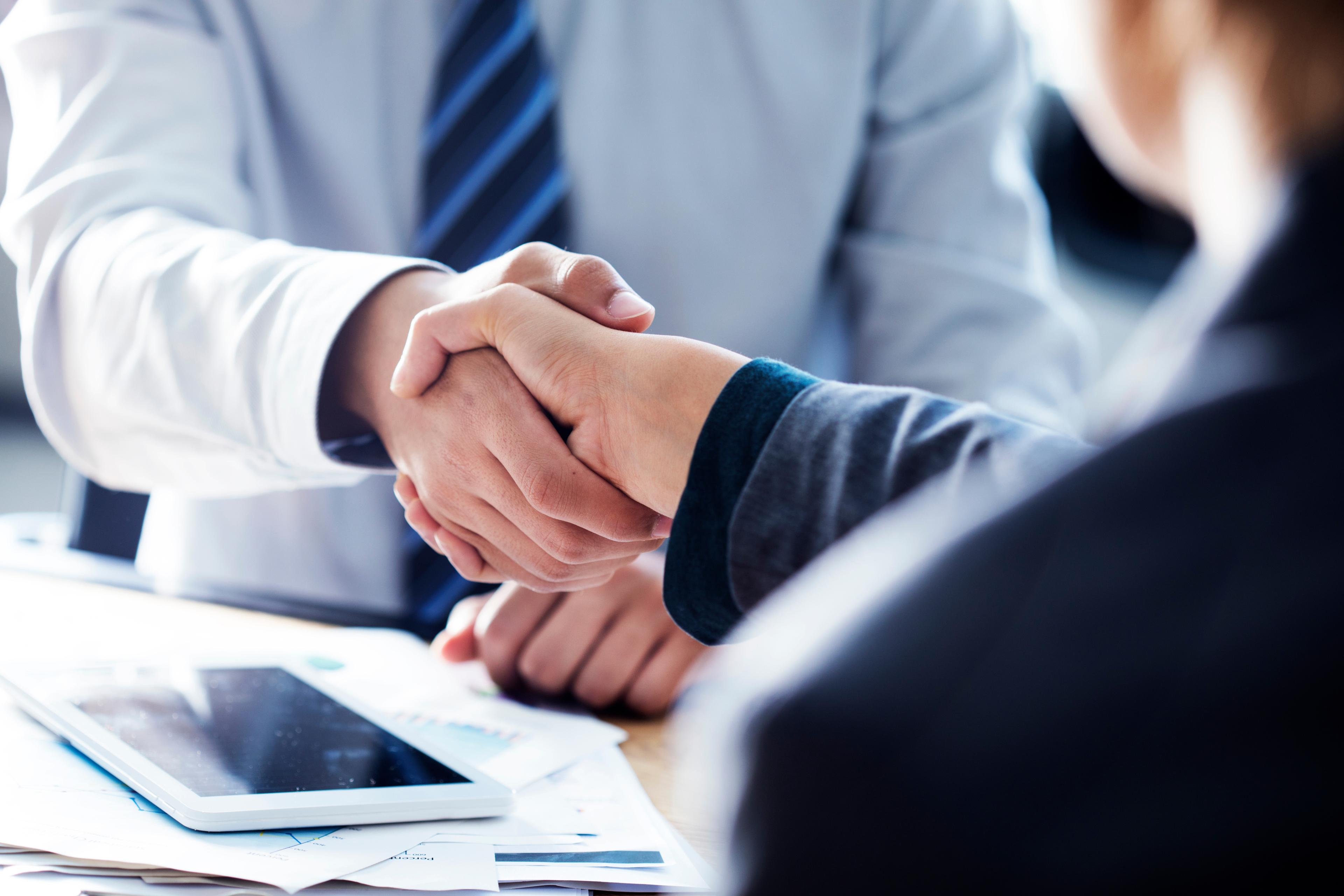 Two professionals shaking hands across a desk